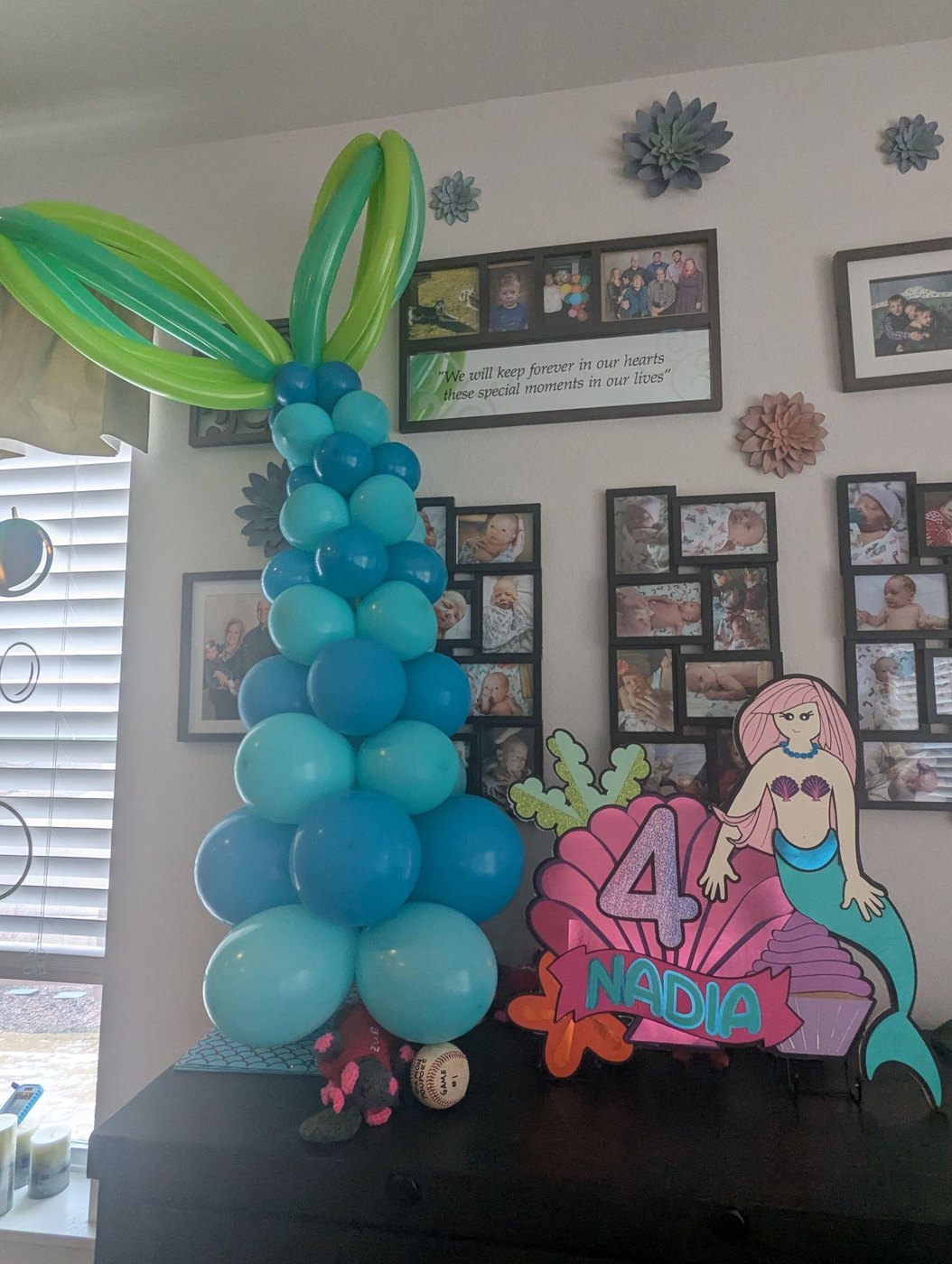 A blue balloon column beside a layered mermaid centerpiece with a number 4 and the name NADIA