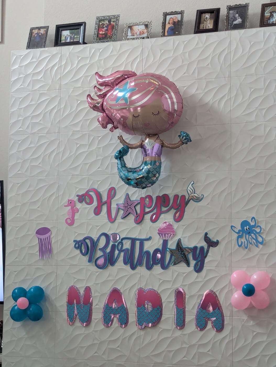Mermaid themed cut letters spelling Happy Birthday NADIA on a wall under a mermaid balloon